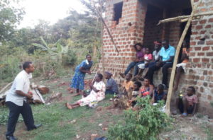 Emmanuel (at far left) visits Irene and her family who now have a home, and a glimpse of hope, because of his ministry.