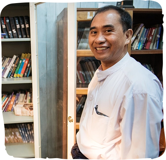 A pastor in front of bookshelves